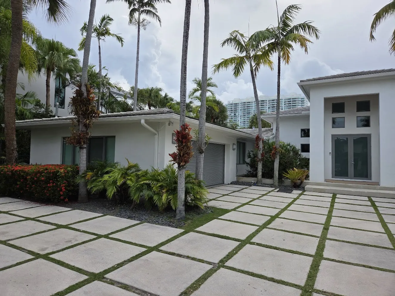 Modern single-story white residence with a paver courtyard and palms