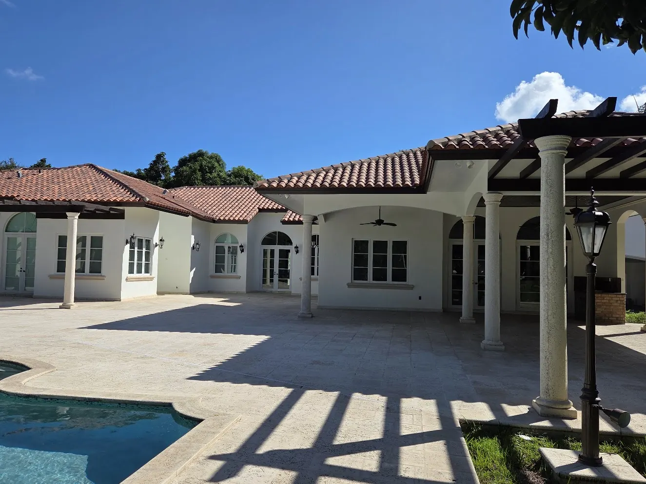 Pool terrace and columned loggia of a white Mediterranean home after an exterior repaint