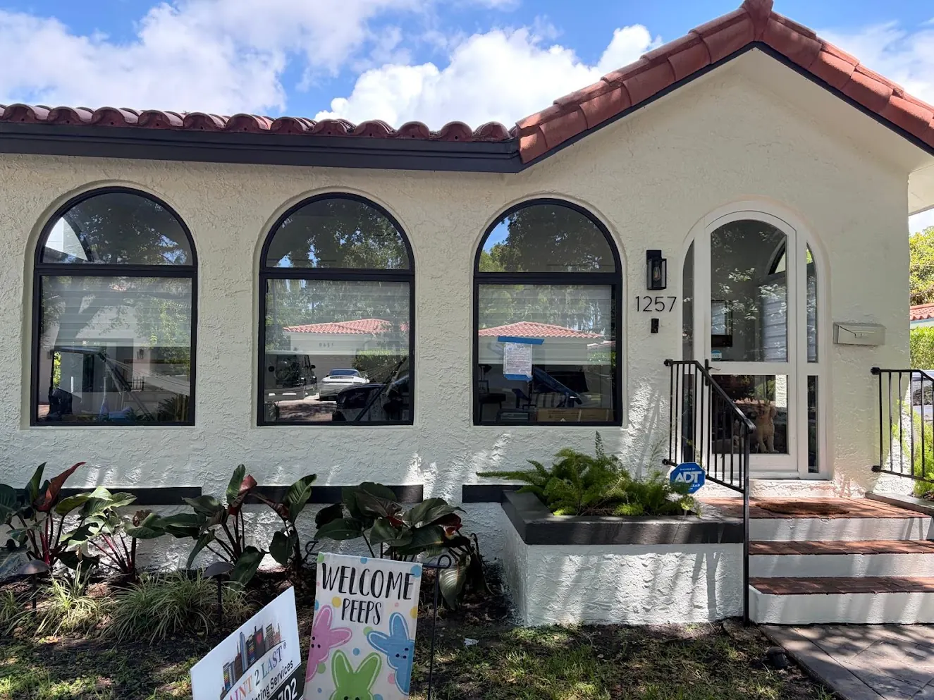 Barrel-tile home with three arched windows and black trim after an exterior repaint