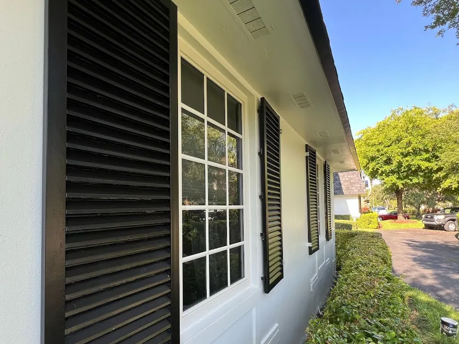 Black louvered shutters on a white stucco wall