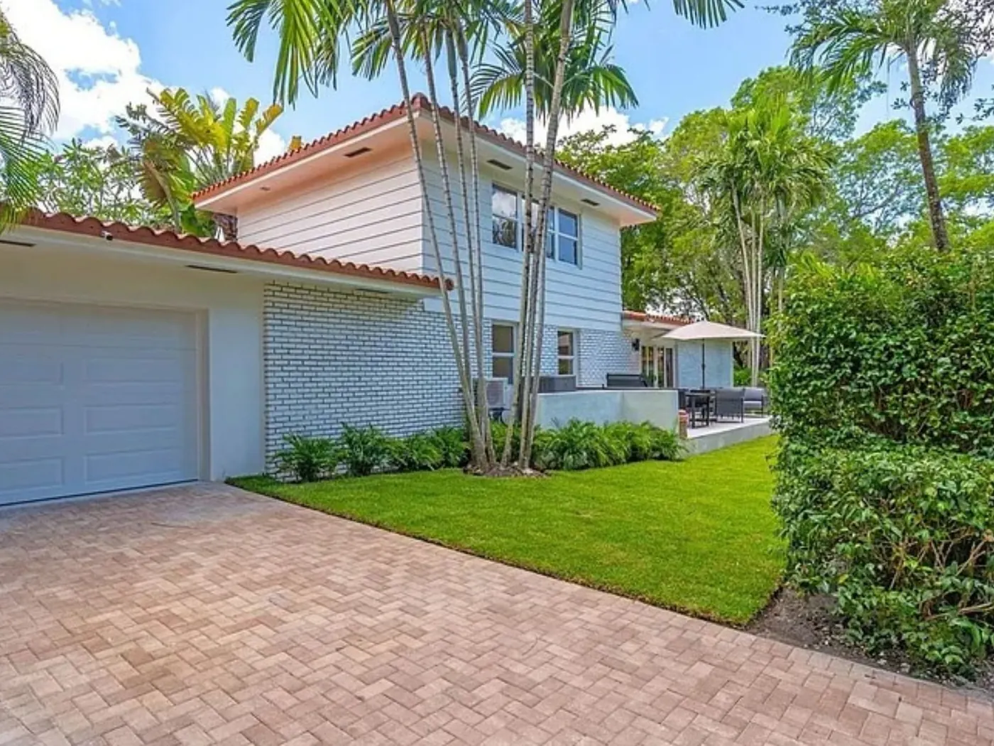 White garage elevation with a paver driveway and palms