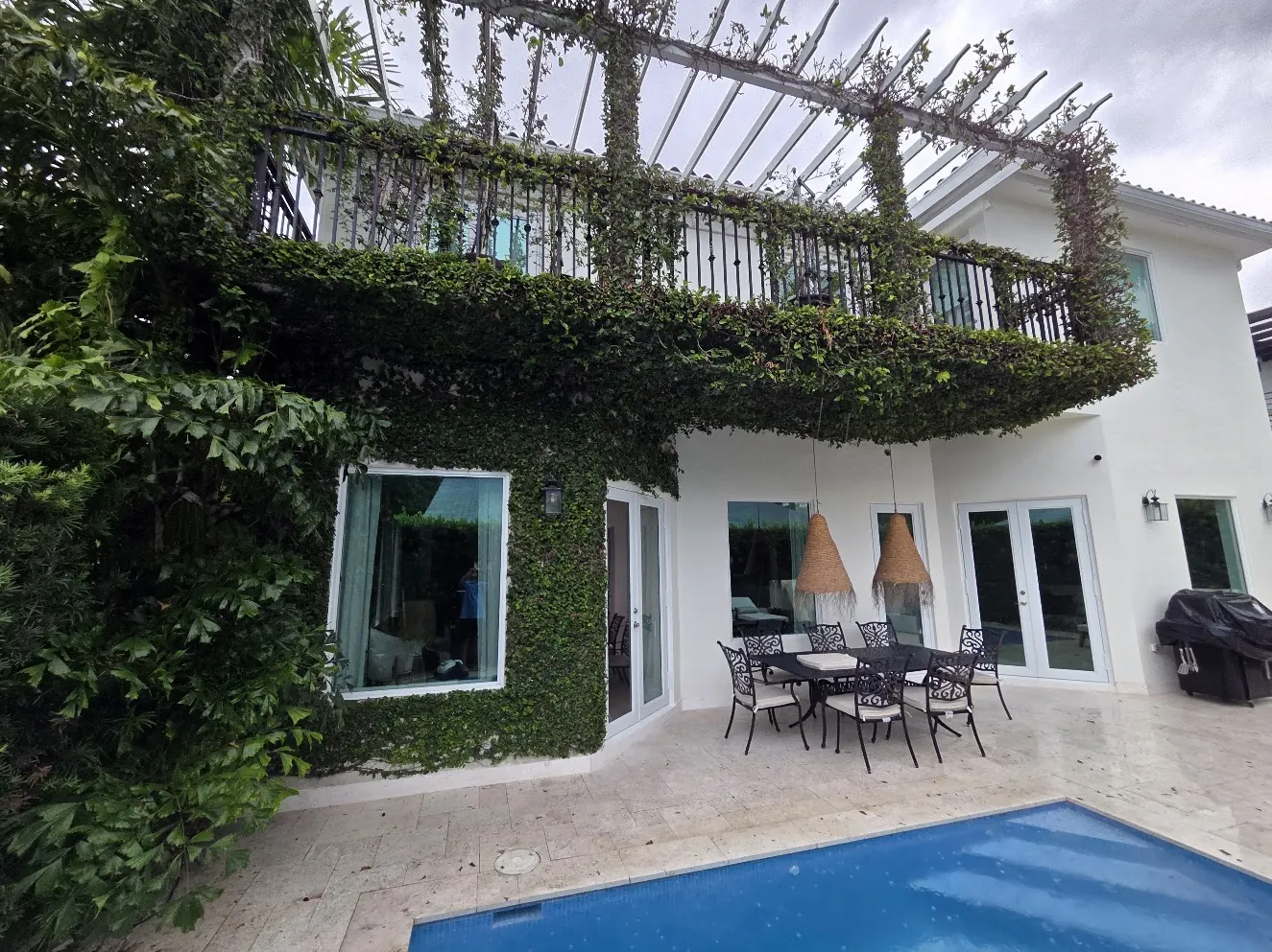 Ivy-covered two-story home with a pool terrace in Miami after an exterior repaint