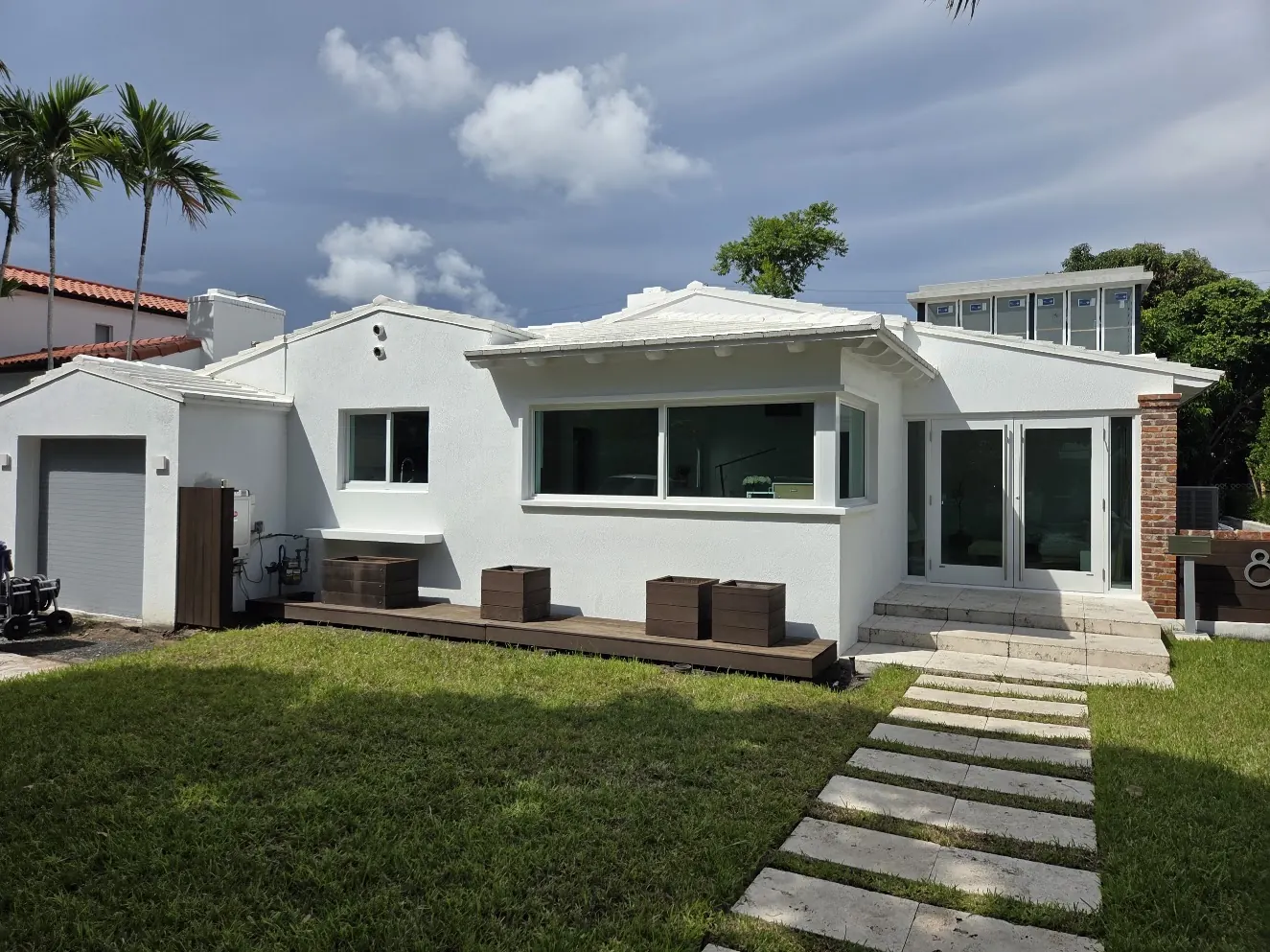 Single-story white Miami Beach home with a new lawn after an exterior repaint