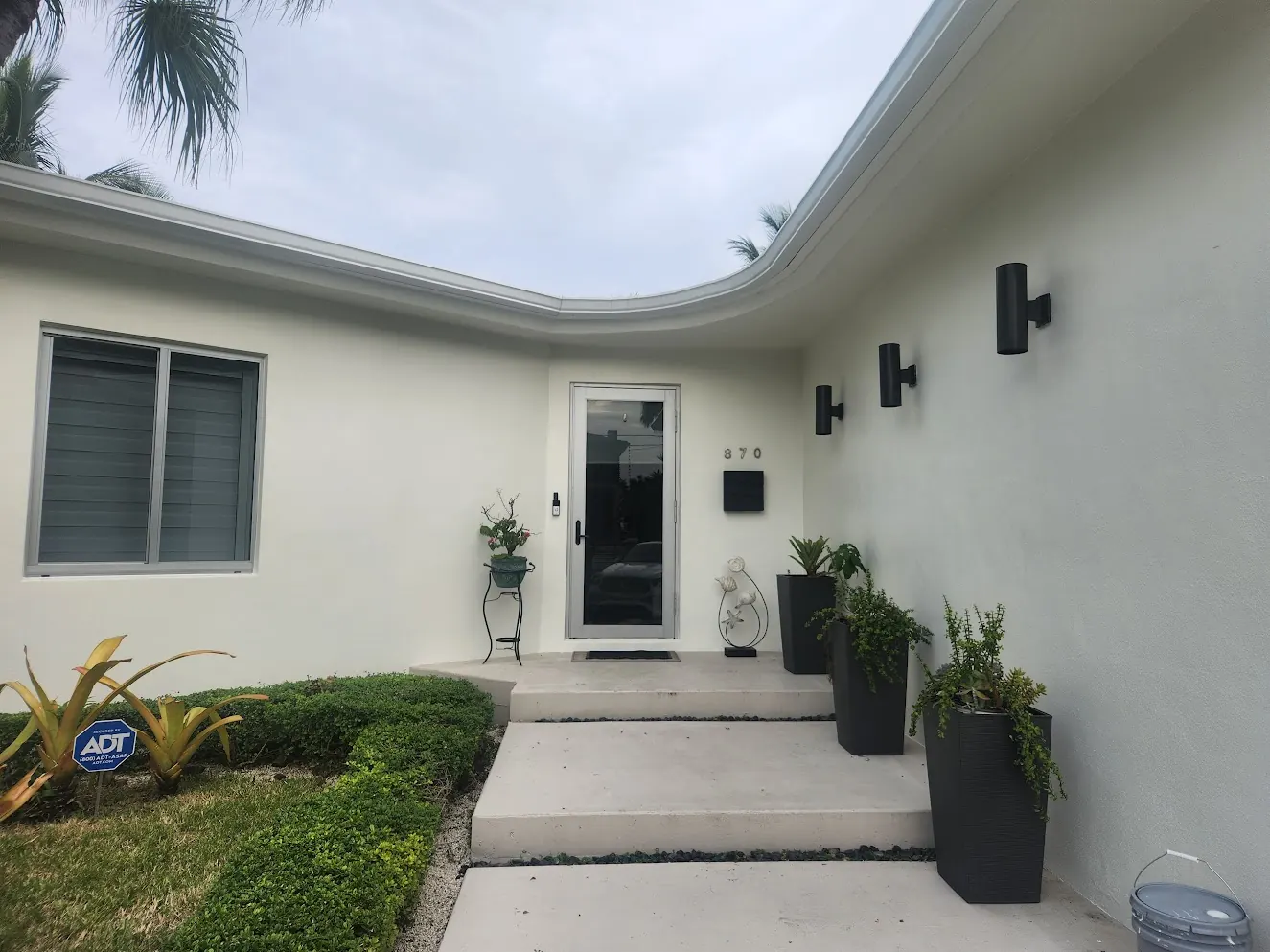 Curved white entry elevation of a Miami Beach home with black fixtures