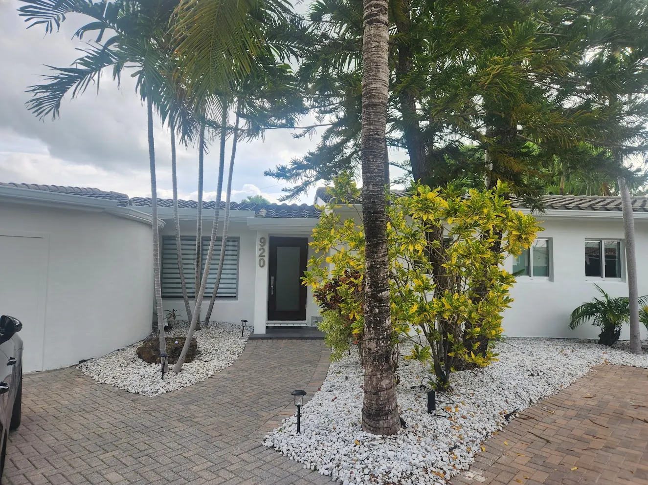 White Miami Beach home with palms and a paver drive after an exterior repaint