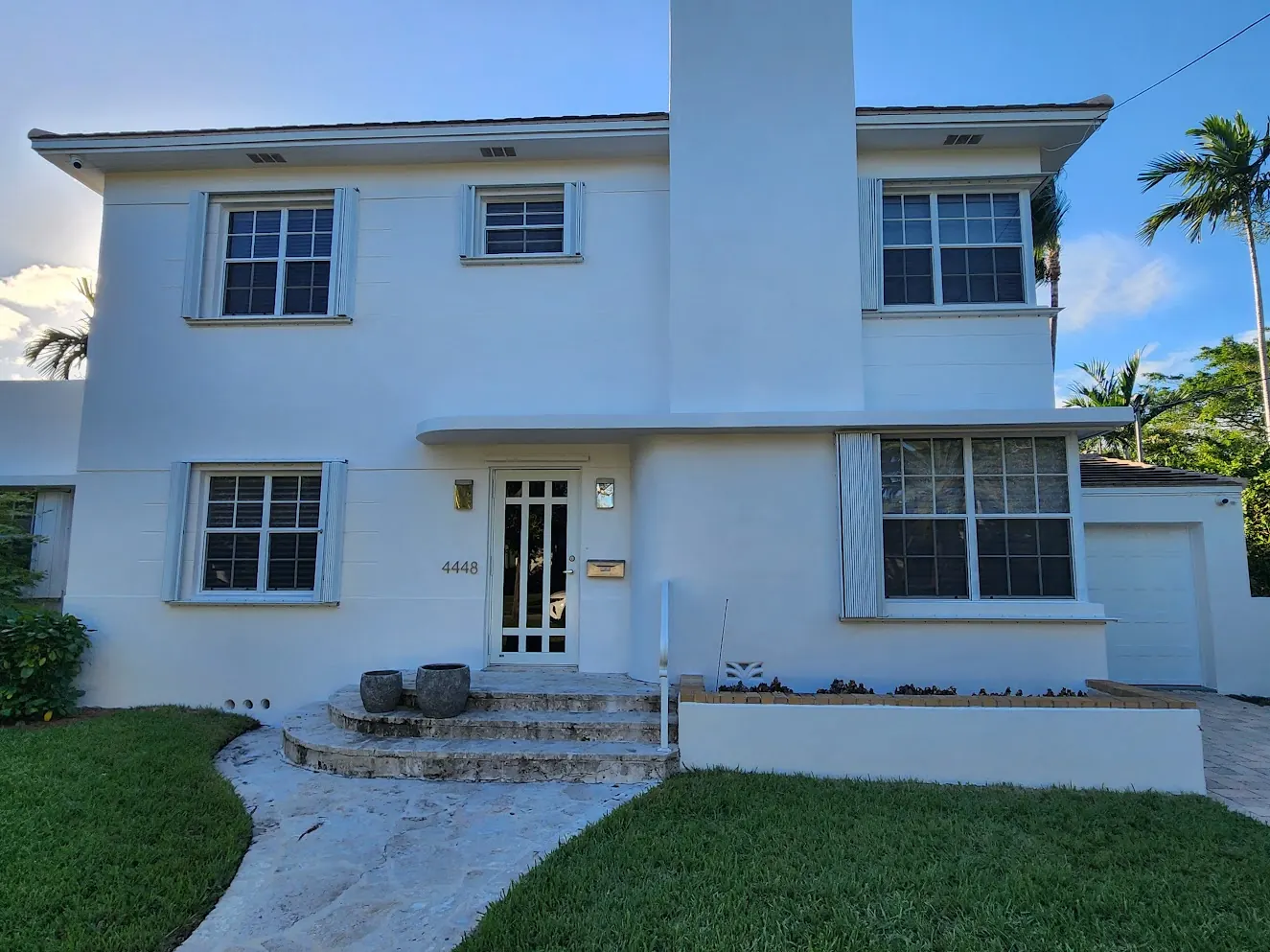 White two-story Miami Beach home with pale blue shutters after an exterior repaint