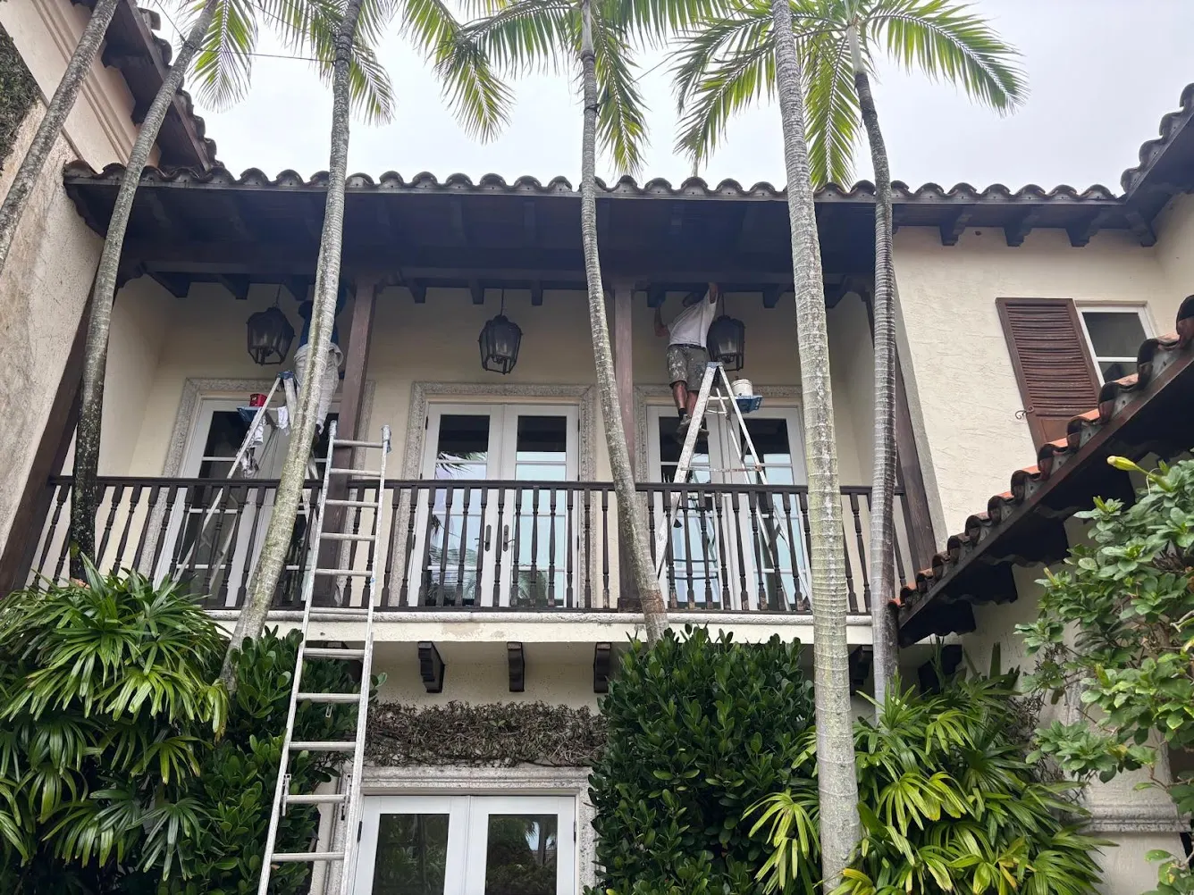 Crew staining the balcony woodwork and eaves from ladders