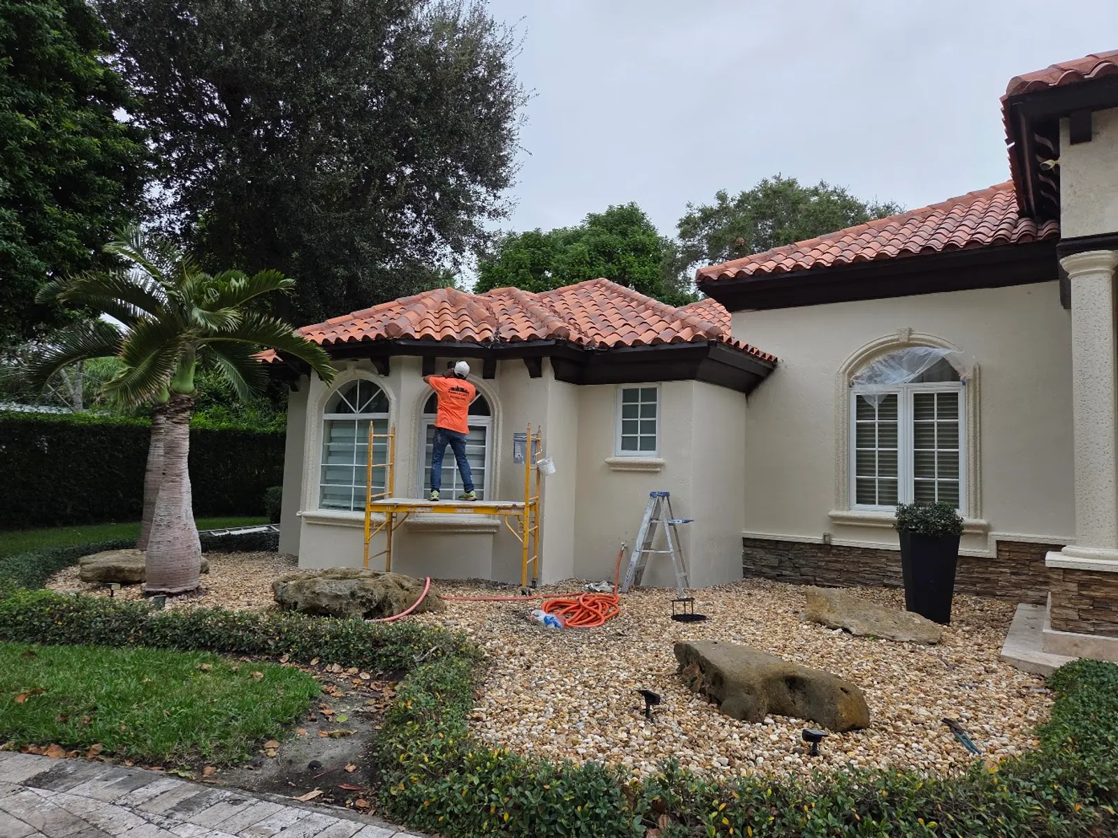 Painter on scaffolding preparing a tile-roof entry