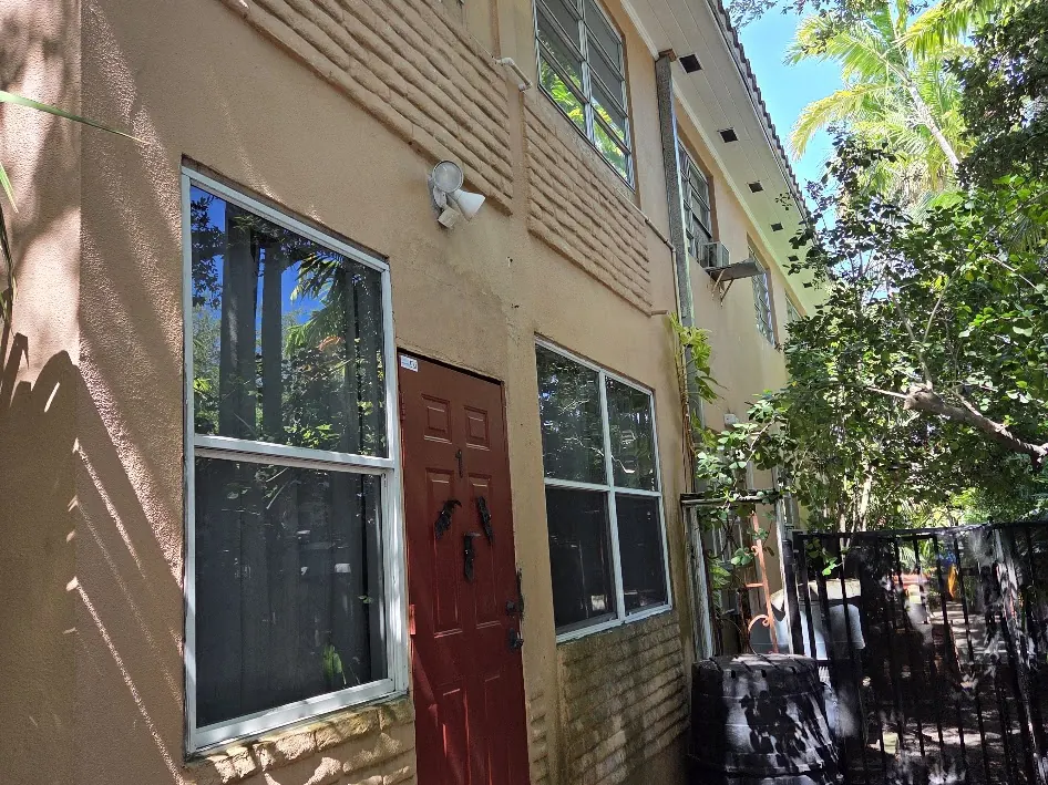 The same entrance elevation before work, with faded stucco and worn door