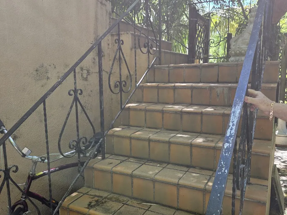 Exterior staircase before work with stained walls and worn railings